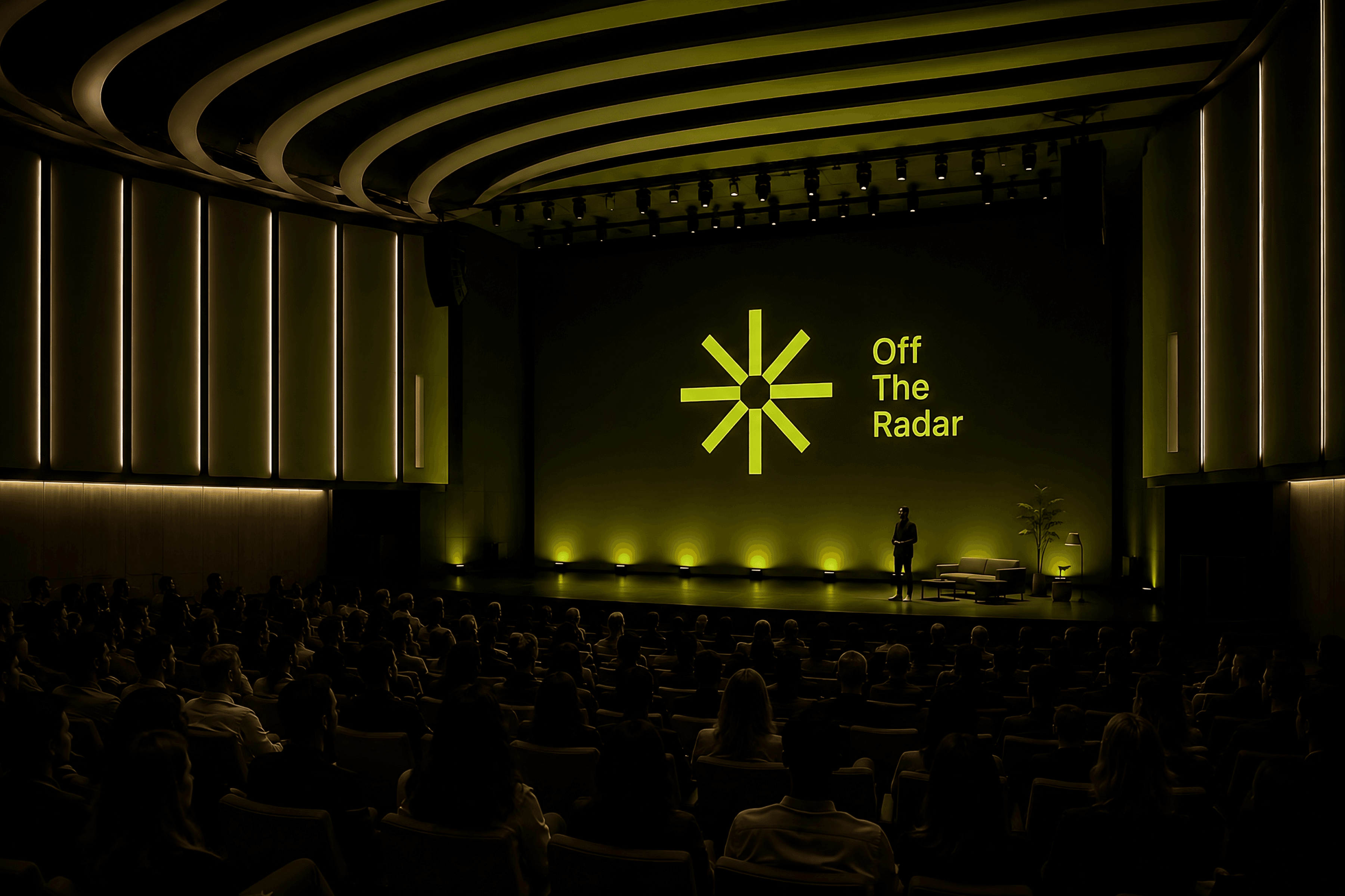 A speaker on stage at Off the Radar, in front of a green-lit Off the Radar wordmark and 8-spoke asterisk.